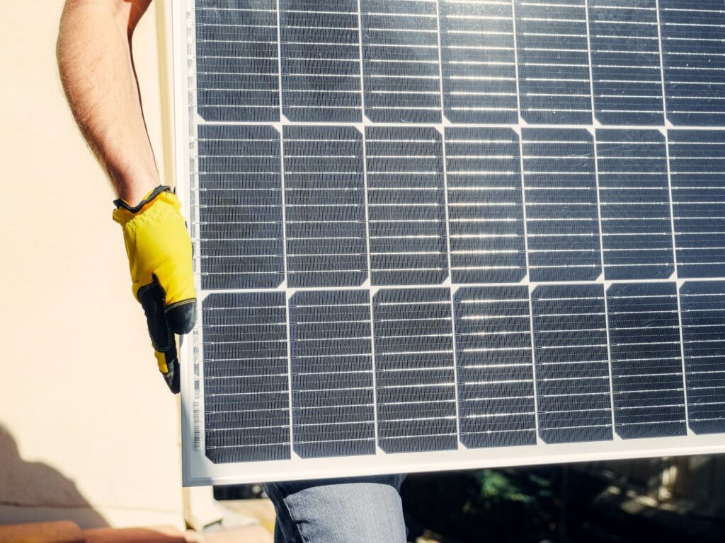 pexels-photo-9875449 Close-up of a person installing a solar panel outdoors under bright sunlight.